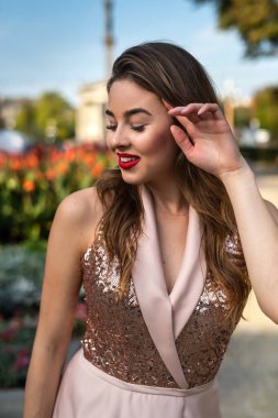 Gece elbisesi giymiş genç ve mutlu bir kadın şehirde yürüyor. yaz zamanı