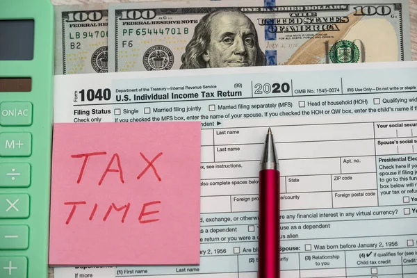1040 US tax form with pen and dollars on desk. Calculating your tax refund