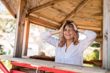Göl kenarı otoparkının yakınındaki ahşap çardakta poz veren kadın model. yaz yaşam tarzı günü