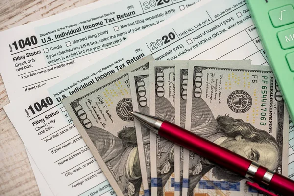 机の上にペンとドルで1040米ドル税フォーム 税金の返金額の計算 — ストック写真