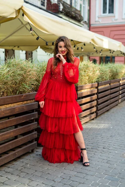 美しいスタイリッシュなブルネットの女性ポーズで赤いドレスで街の背景 — ストック写真