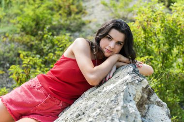 Güzel bir kız kayalıklarda büyük bir taşın üzerinde dinleniyor. Yaşam biçimi