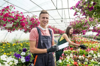 Genç çift, bahar mevsiminde seralarında bitki yetiştirirken panoya not alıyor.