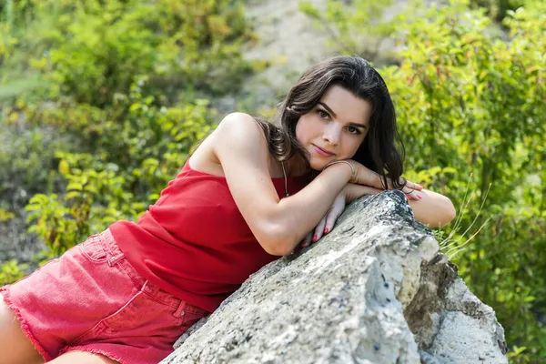 Güzel bir kız kayalıklarda büyük bir taşın üzerinde dinleniyor. Yaşam biçimi