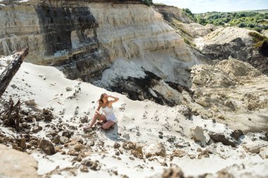Dişi turist, kum havuzunda zor bir günün ardından oturur ve dinlenir. Güneşli bir günde tatil. özgürlük