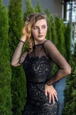 thuja occidentalis ağaçlarının yanında siyah moda elbiseli çekici bir kadın portresi. Yaşam biçimi