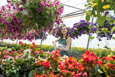 Serasında sulayan genç bir kadın güzellik çiçekleri var. Bitkilerle ilgilenme kavramı