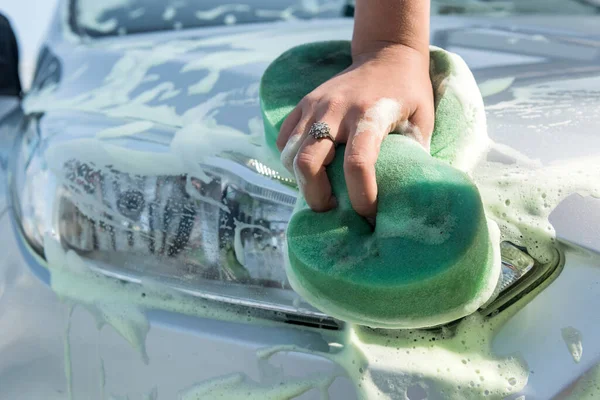 女性の手を使用してスポンジ石鹸泡車の洗浄ステーションで彼女の車を掃除 — ストック写真