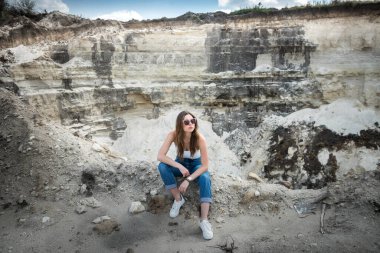 Güzel kadın taş ocağında kumda oturuyor. Yaz tatilinin tadını çıkar.