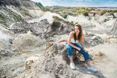 Güzel kadın taş ocağında kumda oturuyor. Yaz tatilinin tadını çıkar.