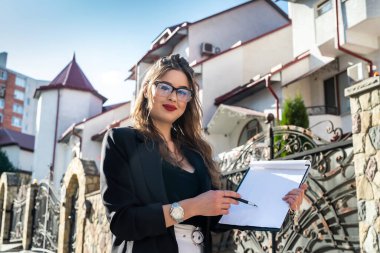 Yeni bir evin önünde duran bir emlakçı kadının portresi. satış veya kira kavramı