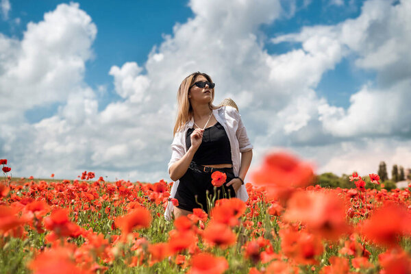 portrait of beautiful ukrainian woman with blond hair, wearing white blouse, posing in poppy field at sunny day, lifestyle