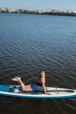 SUP yönetim kurulundaki genç ve güzel kadın şehir gölünde yaz yaşam tarzının tadını çıkarıyor. 