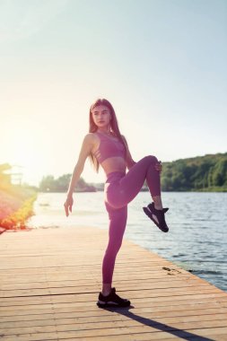 Güzel, zayıf bir kadın yoga yapıyor ya da göl kenarında egzersiz yapıyor. Sağlıklı yaşam tarzı.