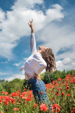 Genç kadın çiçek açan haşhaş tarlasının yanında duruyor. Dışarıda mutlu bir kız, yaşam tarzı.