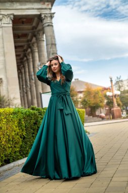 Mükemmel bir yaz gününde yeşil elbiseli, rahat ve kameraya poz veren genç, zarif bir kadın. 