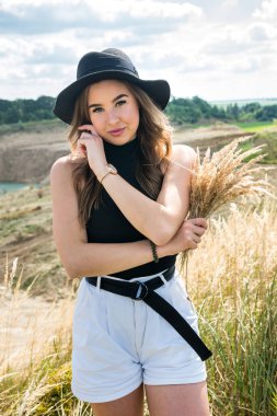 Çekici genç bir kadın yaz mevsiminde çimenlikte dikilirken eğleniyor. özgürlük