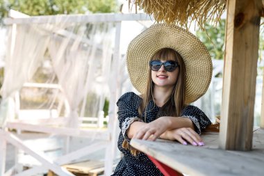 Genç bayan yazın beyaz çardakta gölün yanında poz veriyor.