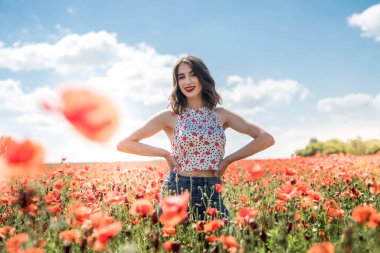 Haşhaş tarlasında yaz zamanı yürüyen genç bir kızın portresi. Doğanın tadını çıkar