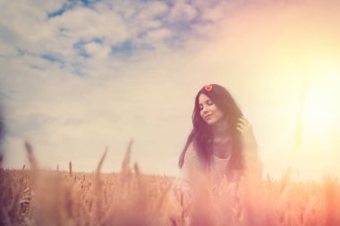 Modaya uygun giyinmiş güzel bir model buğday tarlasında yürüyor. Yaşam tarzının tadını çıkar