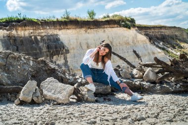 Çölün kumları arasında yürüyen genç bir kadın ya da mavi gökyüzü ile taş ocağı, doğada mükemmel bir yaşam tarzı.