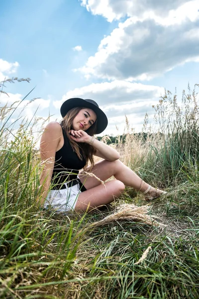 Çekici genç bir kadın yaz mevsiminde çimenlikte dikilirken eğleniyor. özgürlük