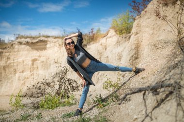 Günlük kıyafetli genç bayan yaz vakti kum kayalıklarında rahatla.
