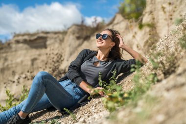 Seksi, güzel genç bir kadın, kum ocağında günlük giysiler giyiyor. Açık hava