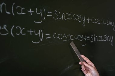 Sınıfa matematik formülleri yazan kadın eli, yakın plan.