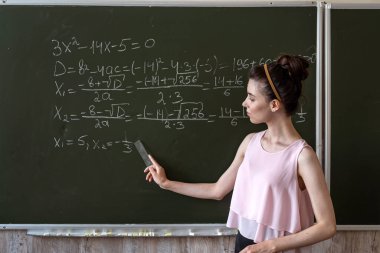 Matematiksel formülleri ve eğitim kavramını tamamlayan karatahtaya yazı yazan zeki bir kız öğrenci. 