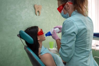 Kadın bir hastayla beyazlatma prosedürüne hazırlanan dişçi.