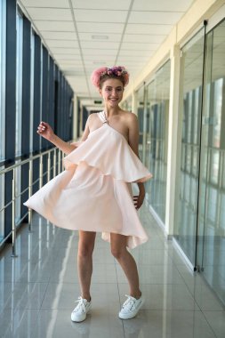 Uzun koridorda pembe elbisesiyle poz veren genç bayan.