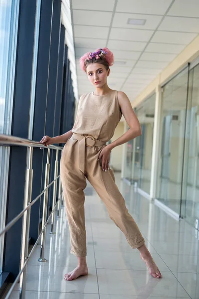 Uzun koridorda pembe elbisesiyle poz veren genç bayan.