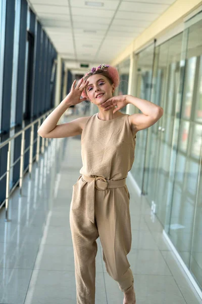 Hoş, çıplak ayaklı bir kadın binanın içinde dikiliyor ve ileriye bakıyor.