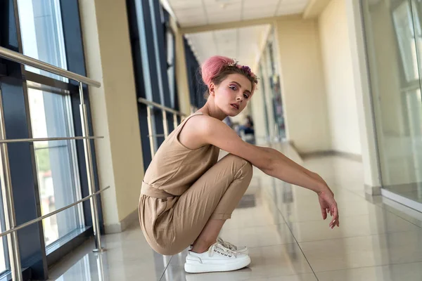 Uzun koridorda pembe elbisesiyle poz veren genç bayan.