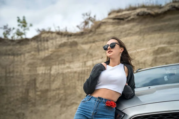 Yaz gezisi sırasında arabanın yanında poz veren genç ve güzel bir kız.