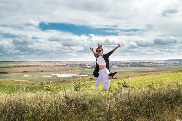 Çekici genç bir kadın yaz mevsiminde çimenlikte dikilirken eğleniyor. özgürlük