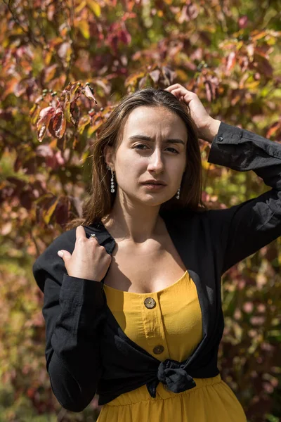 Sonbahar yapraklarına yakın genç bir kadının portresi parkta ılık bir ışıkta.