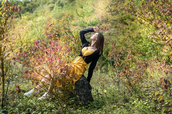 Güzel ve tatlı bir kız. Renkli yaprakların yanında. Parkta, sonbahar atmosferinde.