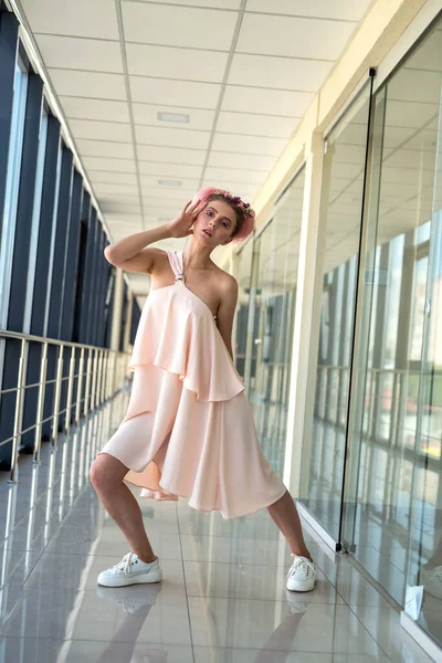 Hoş, çıplak ayaklı bir kadın binanın içinde dikiliyor ve ileriye bakıyor.