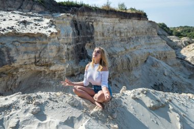 Genç bir kadın kum ocağında hafif egzersizler yapıyor. yoga. Doğada rahatlama. güneşli bir gün