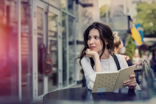 年轻美丽的姑娘坐在咖啡店里等着她的卡布奇诺 — 图库照片