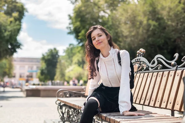 若いです可愛いです女性は市内公園のベンチに座って背景 — ストック写真