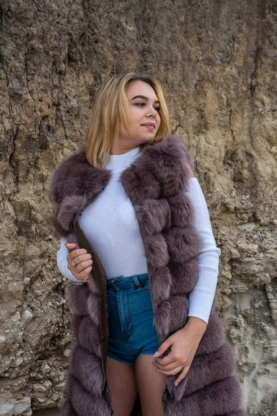 ゴージャスファッションモデルは 暖かい秋の晴れた日に乾燥した空の砂の採石場に立って毛皮のコートを着用 — ストック写真