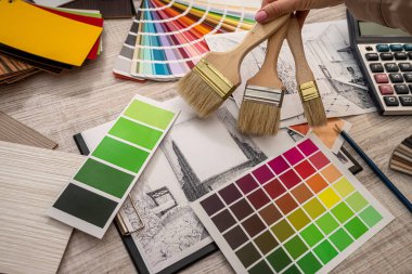 Kadın iç mimar, ofiste ev çizimi ile çalışarak paletten renk seçer