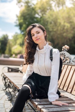 Şehir parkında halka açık bir bankta oturan genç ve güzel bir kadın. 