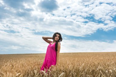 Modaya uygun giyinmiş güzel bir model buğday tarlasında yürüyor. Yaşam tarzının tadını çıkar