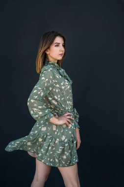  Siyah duvarın yanında zarif yeşil elbiseli güzel bir kadın. Moda kadın portresi