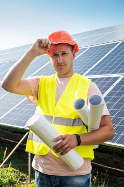 Güneş enerjisi santralinde çalışan üniformalı bir mühendis. Güneş istasyonu geliştirme kavramı