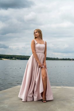 Genç kadın yaz tatilinde yalnız poz veriyor göl kenarında şirin bir elbise içinde, yaşam tarzıyla